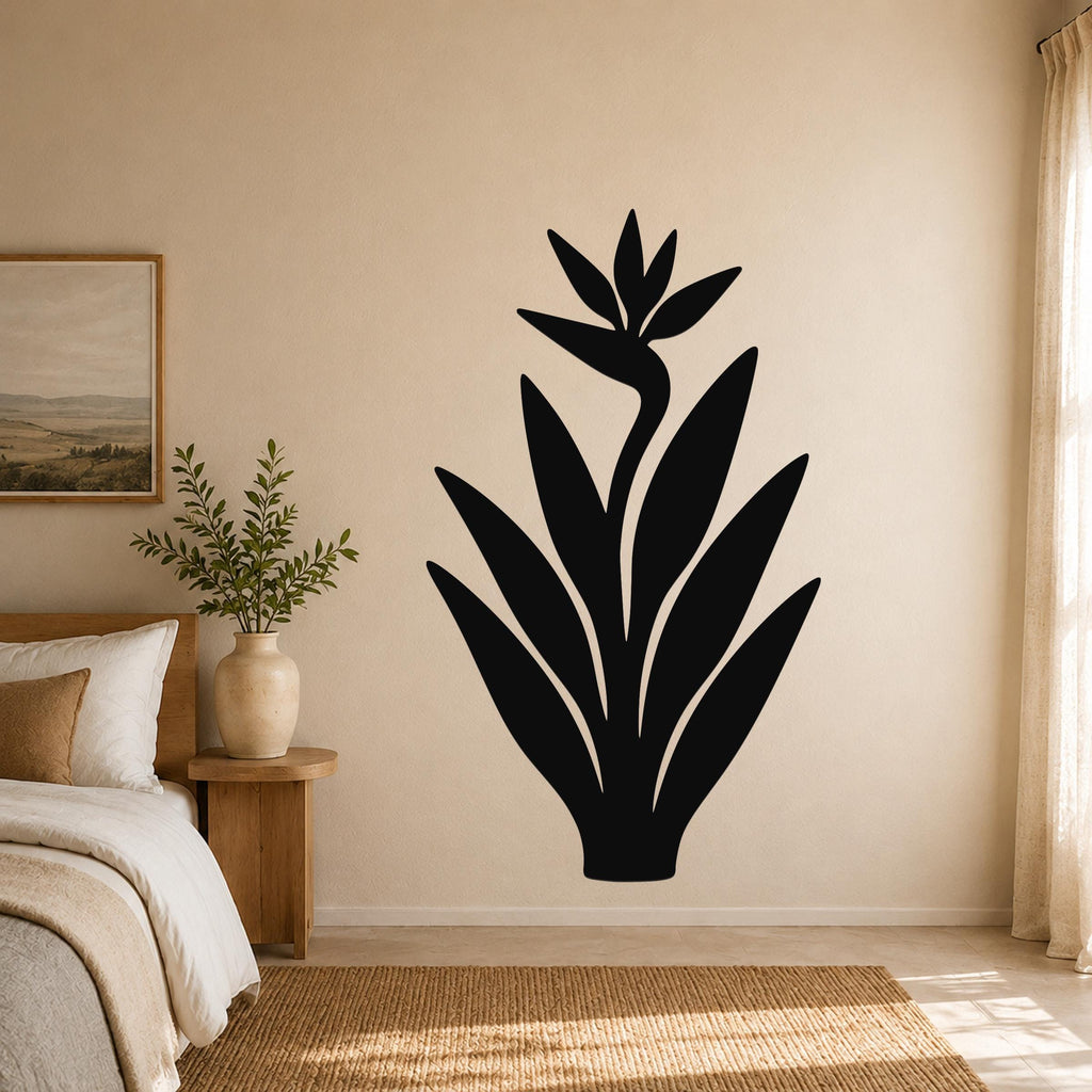Black metal Bird of Paradise wall art silhouette with flower and leaf cutouts, mounted on a beige bedroom wall above a woven rug.