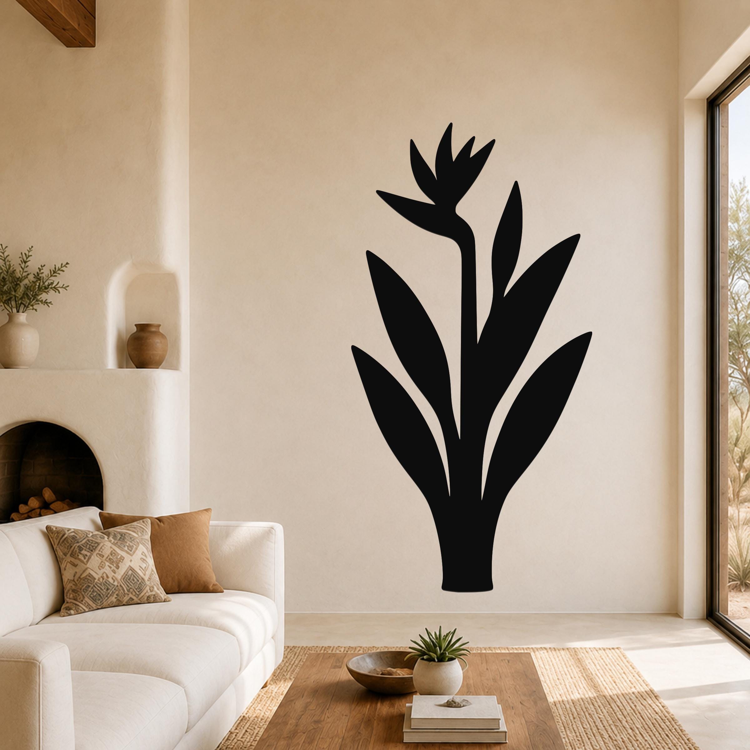 Black metal Bird of Paradise wall art silhouette mounted on a living room wall above a white sofa.