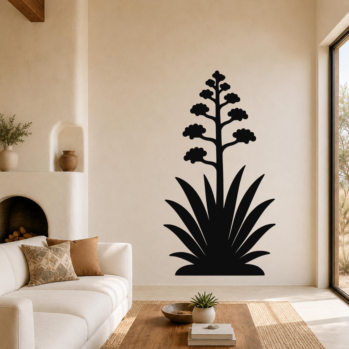 Black metal agave wall art with blooming flower cutout, mounted on a living room wall above a sofa.