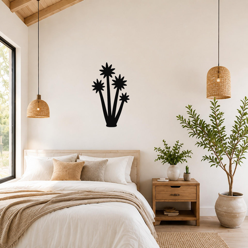 Black metal yucca wall art with star-shaped cutouts, mounted on a bedroom wall above a bed.