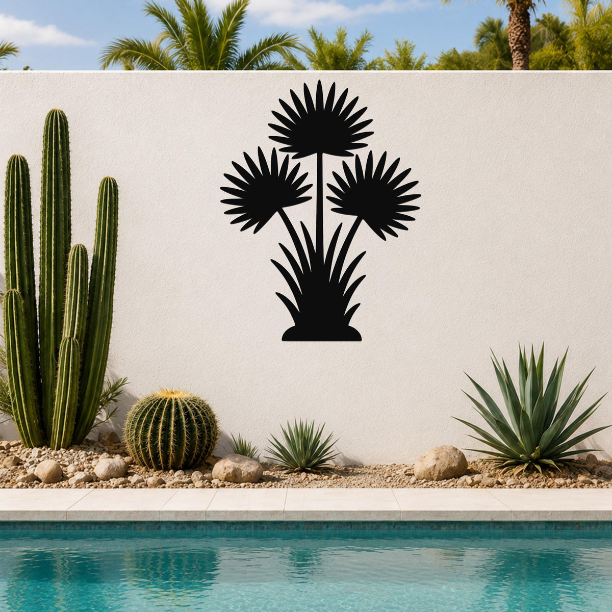 Black metal fan palm tree wall art with three frond silhouettes, mounted on a white outdoor wall above a poolside garden.