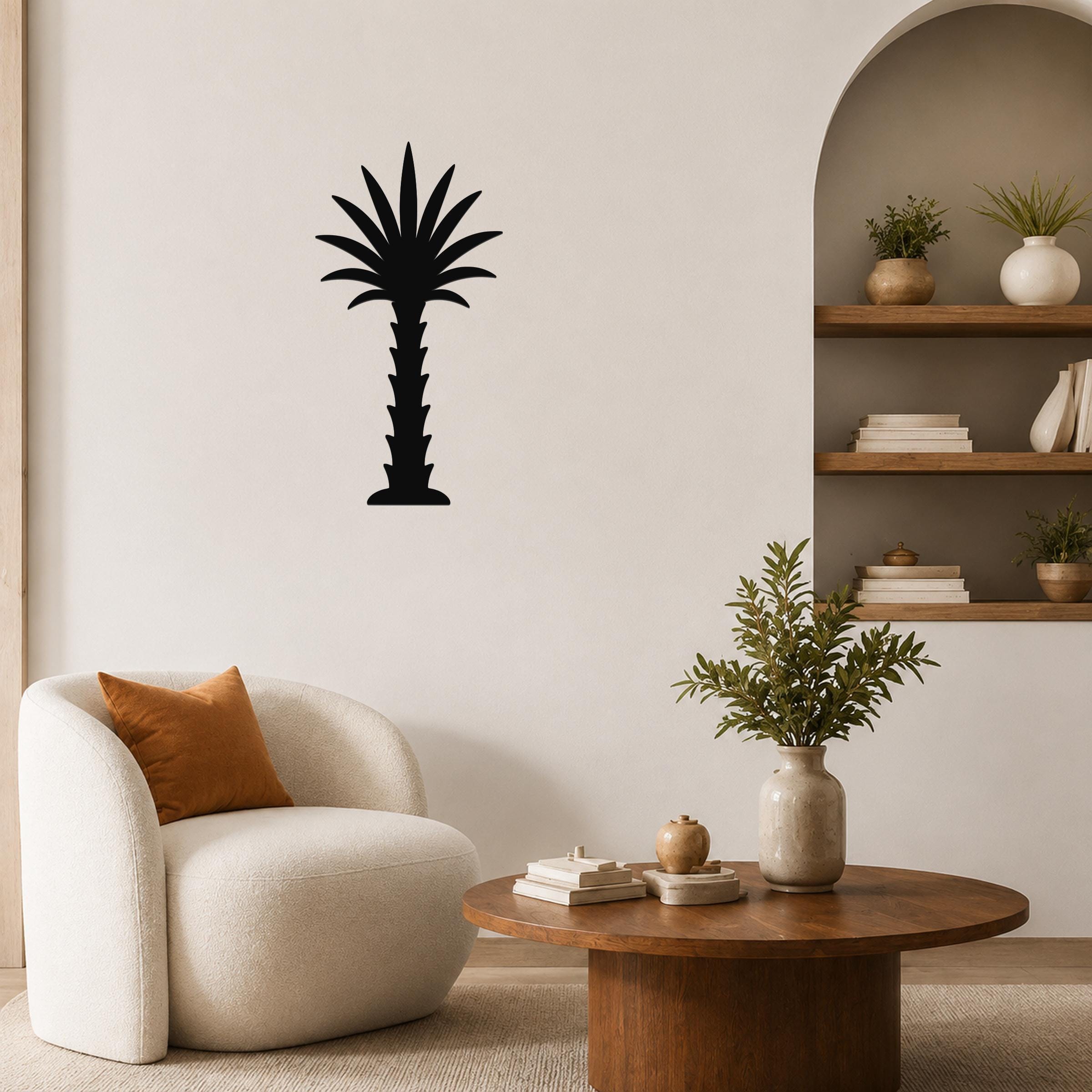 Black metal palm tree wall art silhouette mounted on a living room wall above a round wooden coffee table.