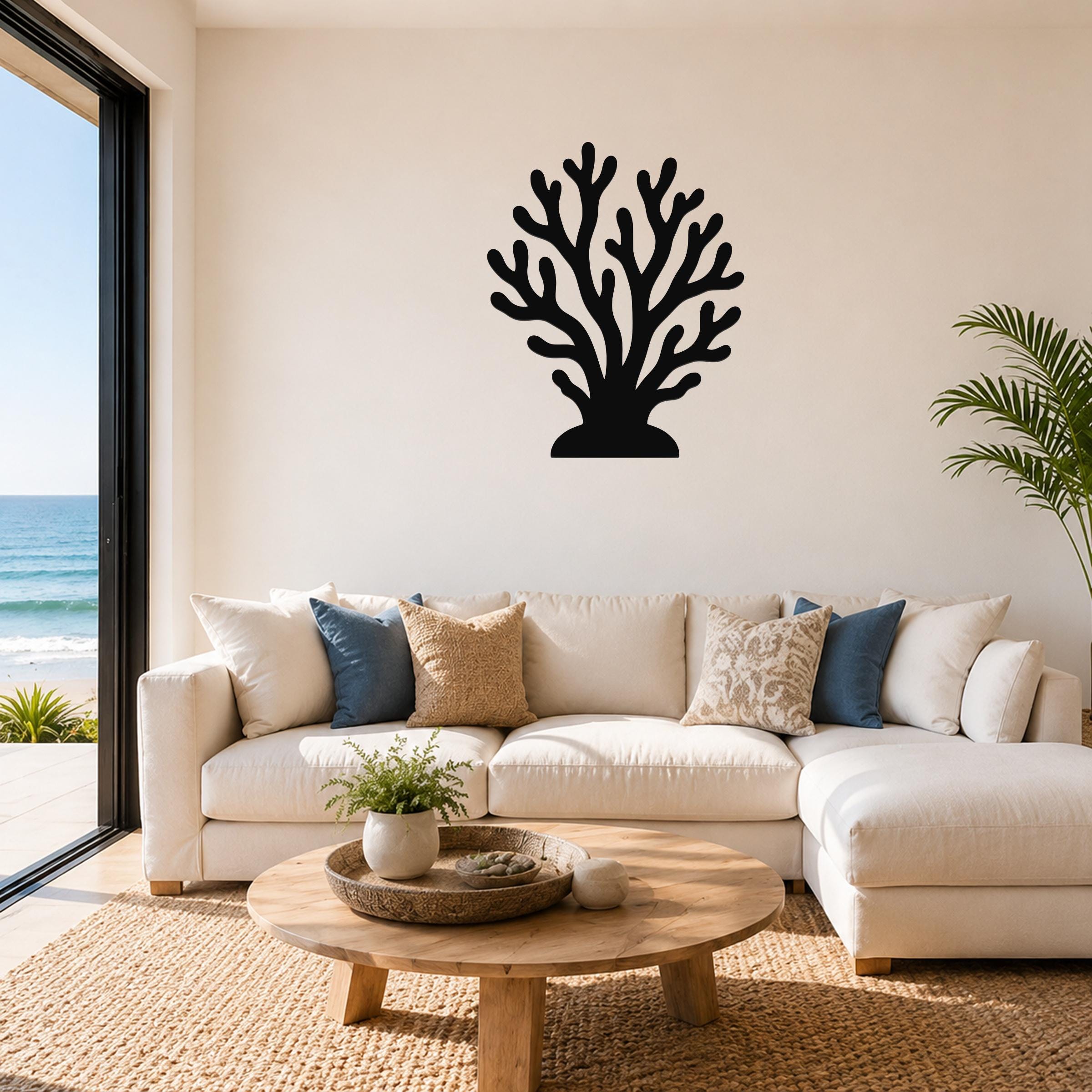 Black metal coral wall art with branching cutouts, mounted above a white sofa in a coastal living room.