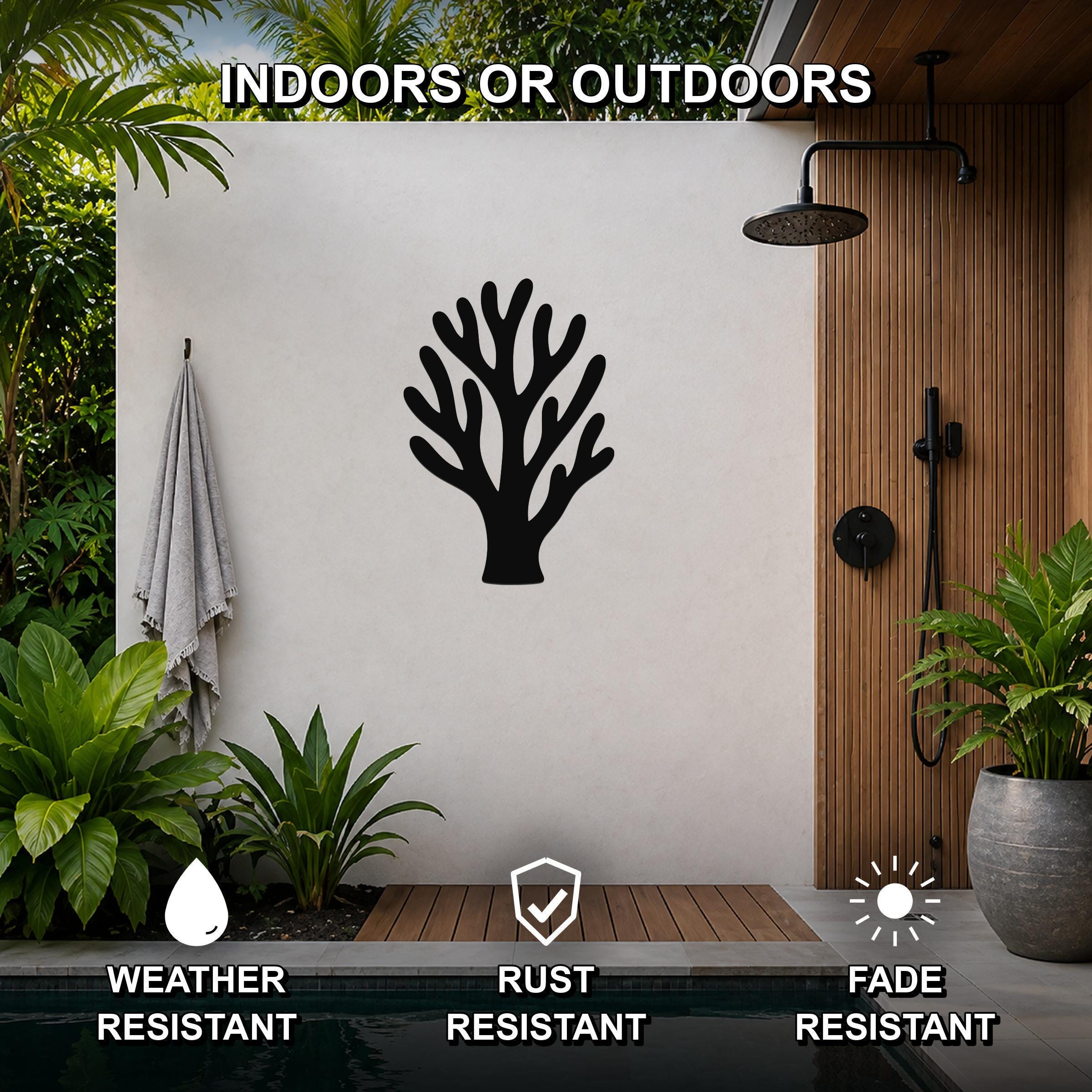 Black metal coral wall art with branching cutouts, mounted on a white outdoor wall beside a pool and shower area.