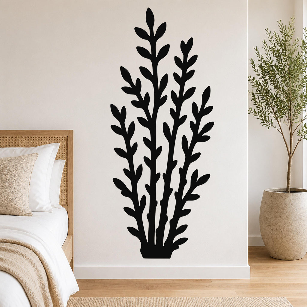 Black metal wall art in a leafy branch silhouette, mounted on a white wall above a bed in a modern bedroom.