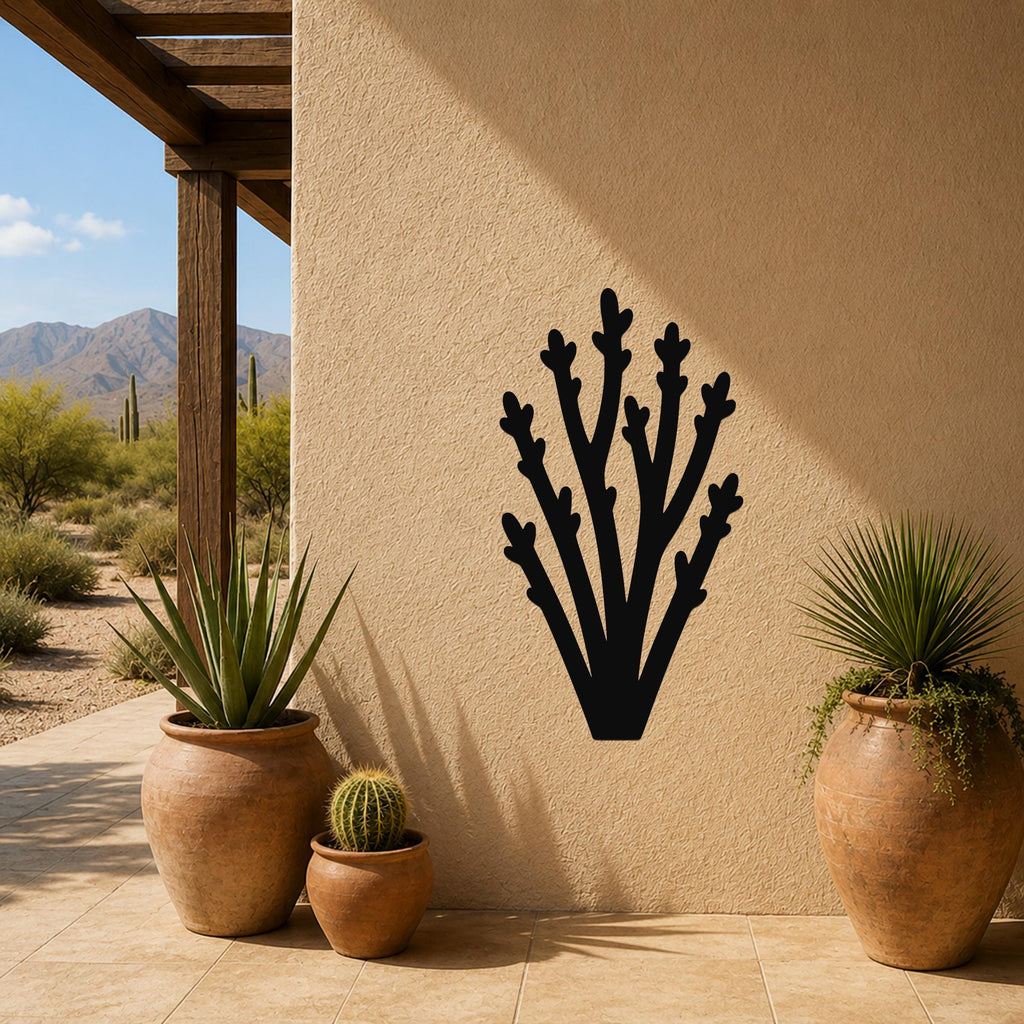 Black metal wall art in a branching cactus silhouette, mounted on a stucco outdoor wall beside potted plants on a patio.
