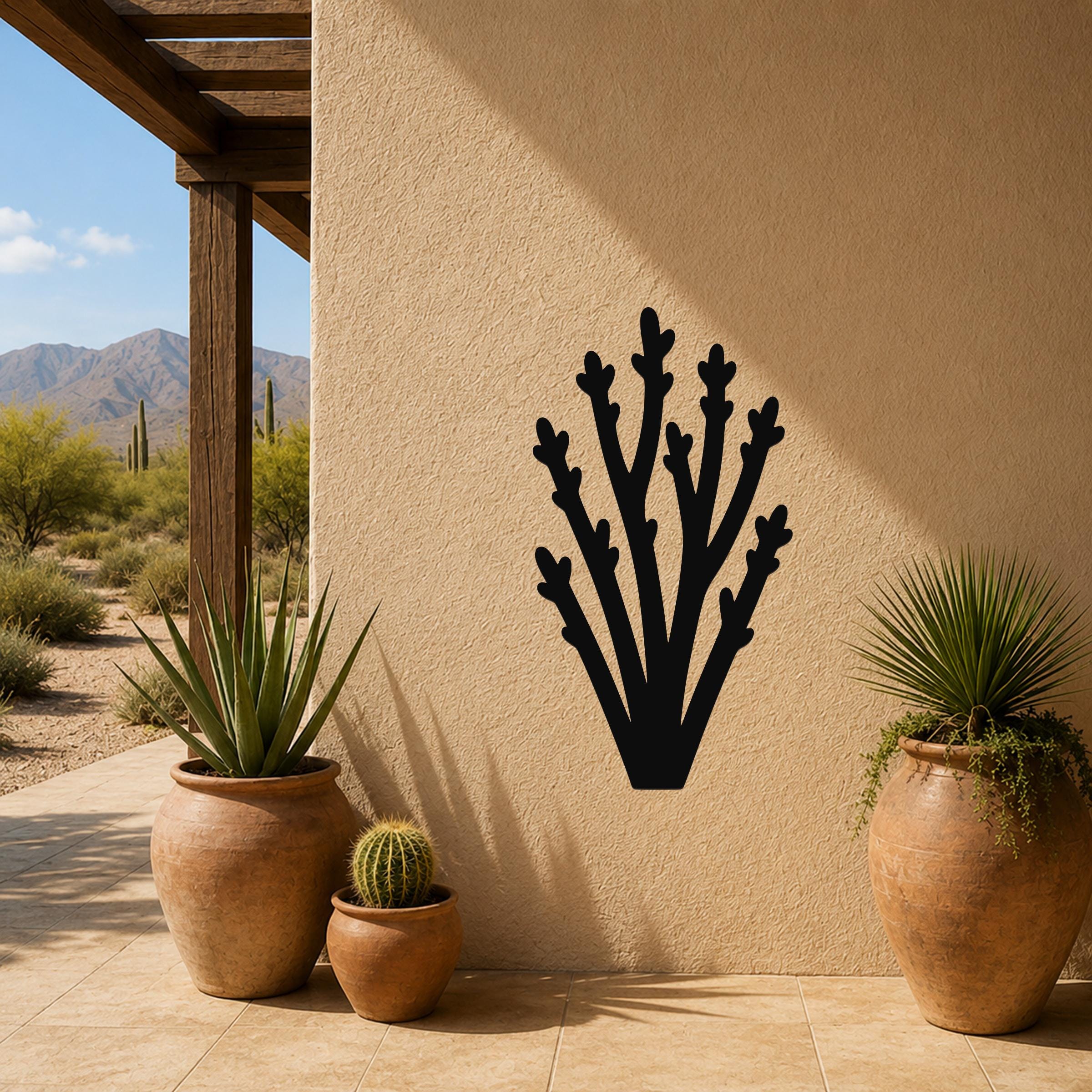 Black metal wall art in a branching cactus silhouette, mounted on a stucco outdoor wall beside potted plants on a patio.