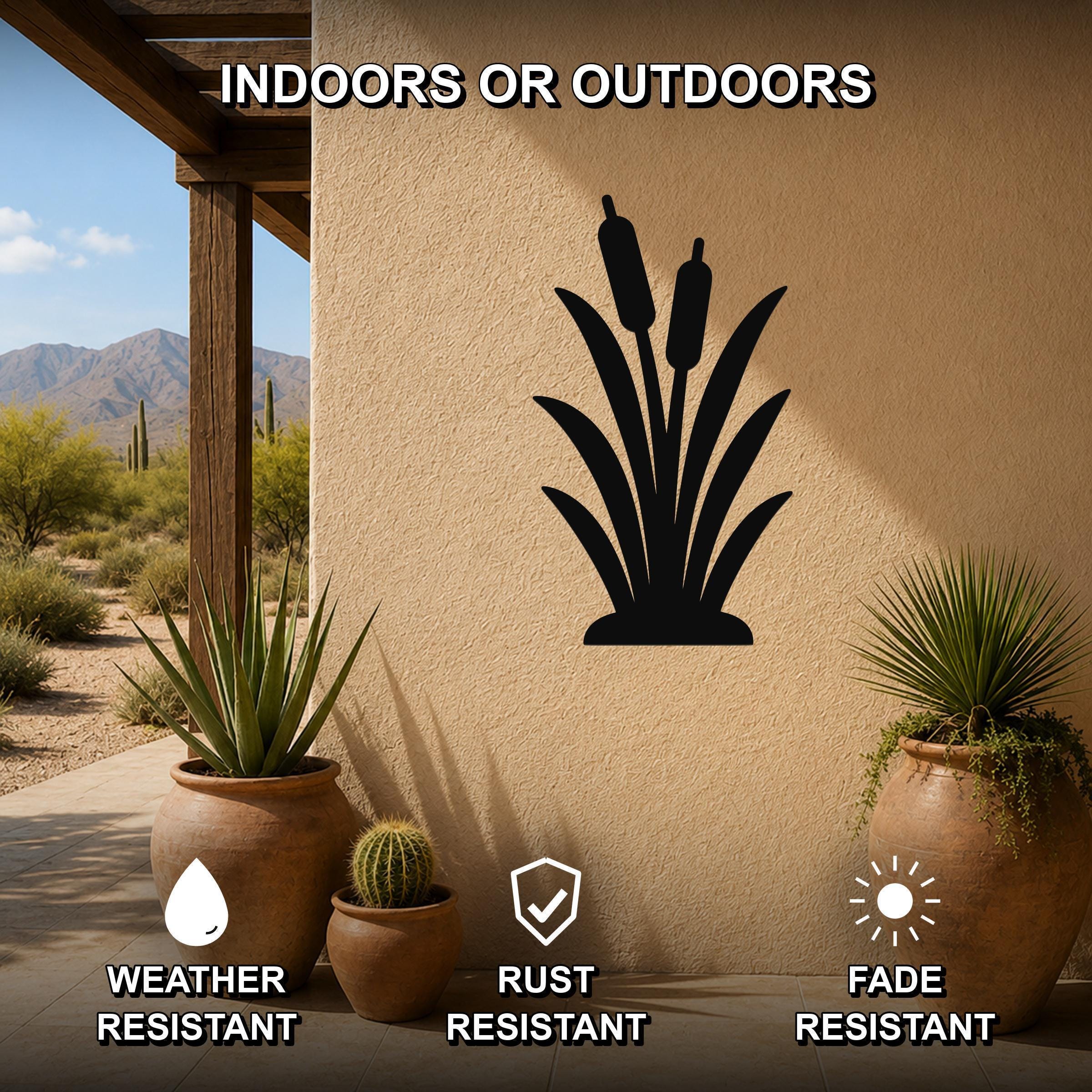 Black metal cattail wall art silhouette mounted on an outdoor stucco wall, displayed on a patio with potted plants and desert scenery in the background.