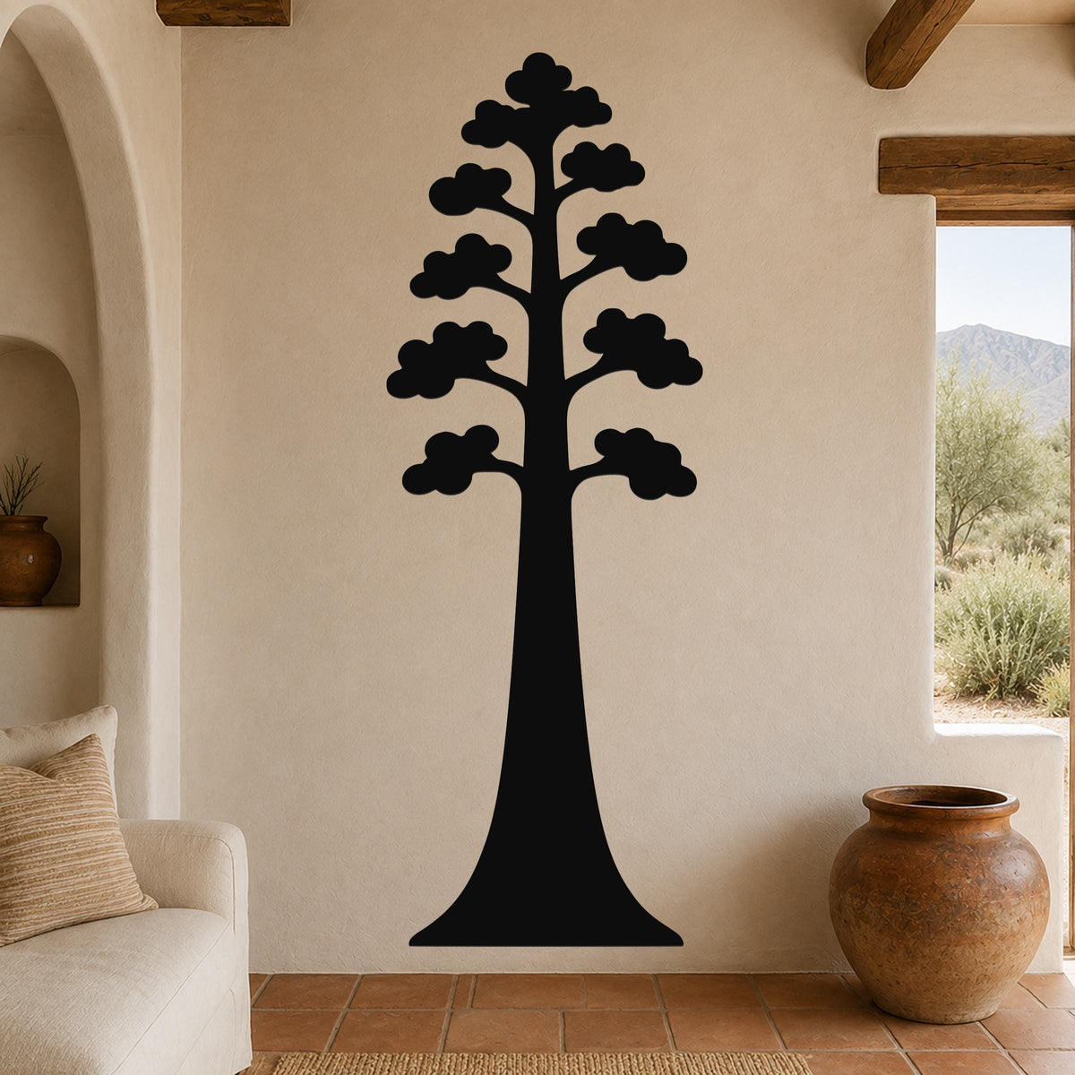 Black metal wall art of a sequoia tree silhouette with layered cloud-like branches, mounted on a beige living room wall above a sofa.