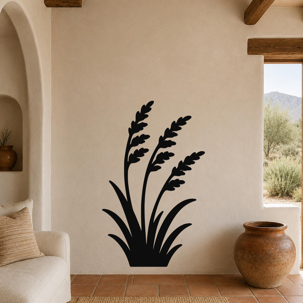 Black metal wall art in a wild grass silhouette design, mounted on a beige stucco wall in a living room with terracotta flooring and wooden beams.