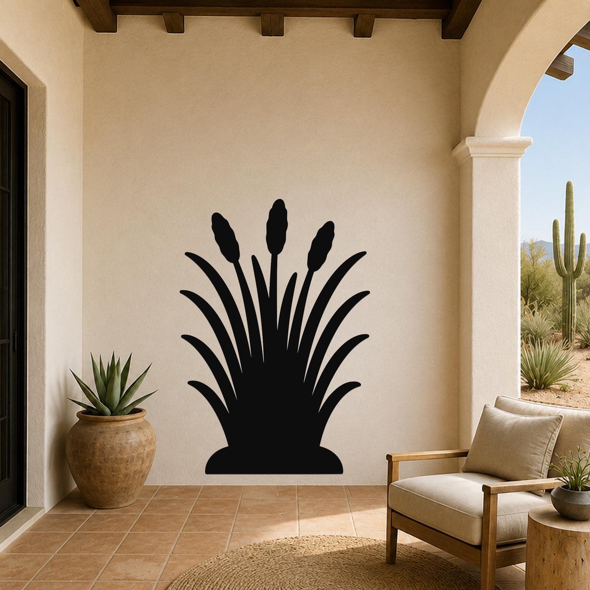 Black metal wall art silhouette of a desert plant with long leaves and seed heads, mounted on a beige patio wall above a wooden chair.