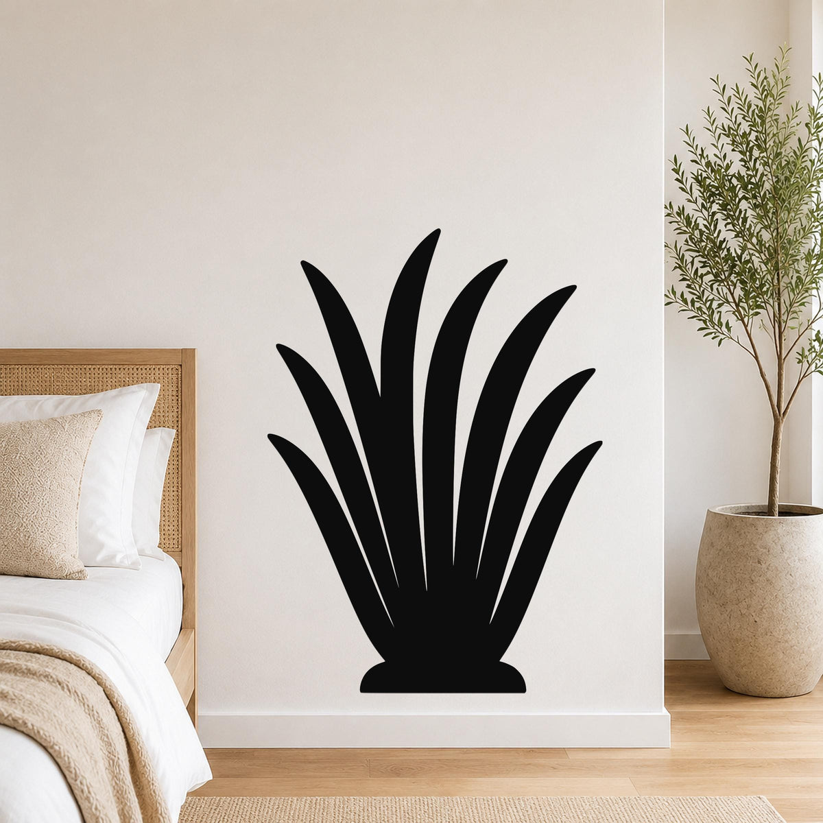 Black metal wall art in a silhouette of a spiky succulent plant, mounted on a white bedroom wall above a bed.