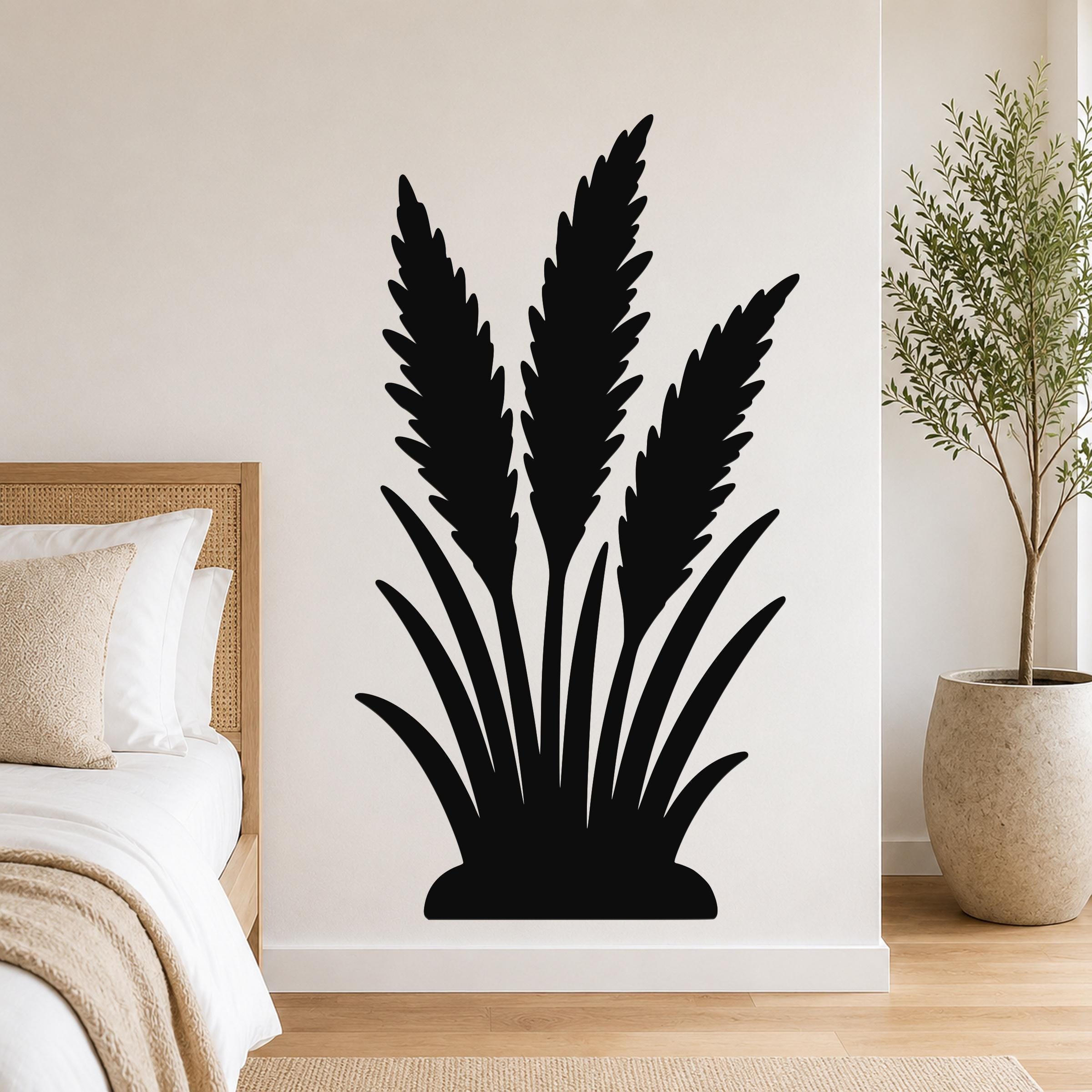 Black metal wall art in a wild grass silhouette design, mounted on a bedroom wall above a bed with a woven headboard.