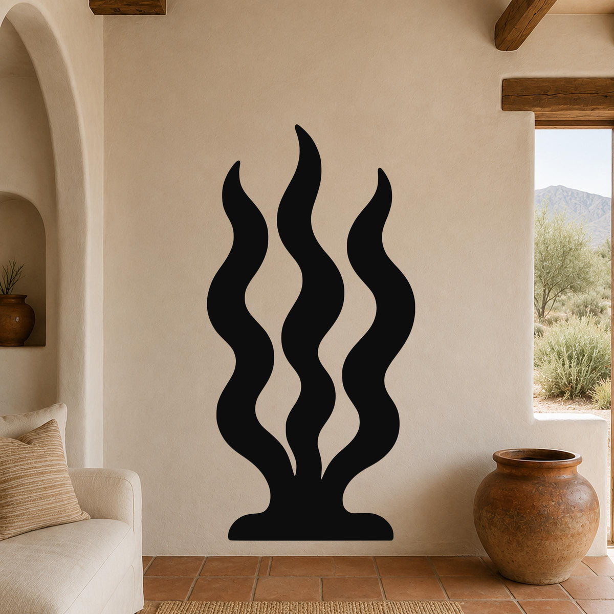 Black metal wall art with a wavy, grass-like silhouette, mounted on a beige wall in a living room with terracotta flooring and wooden beams.