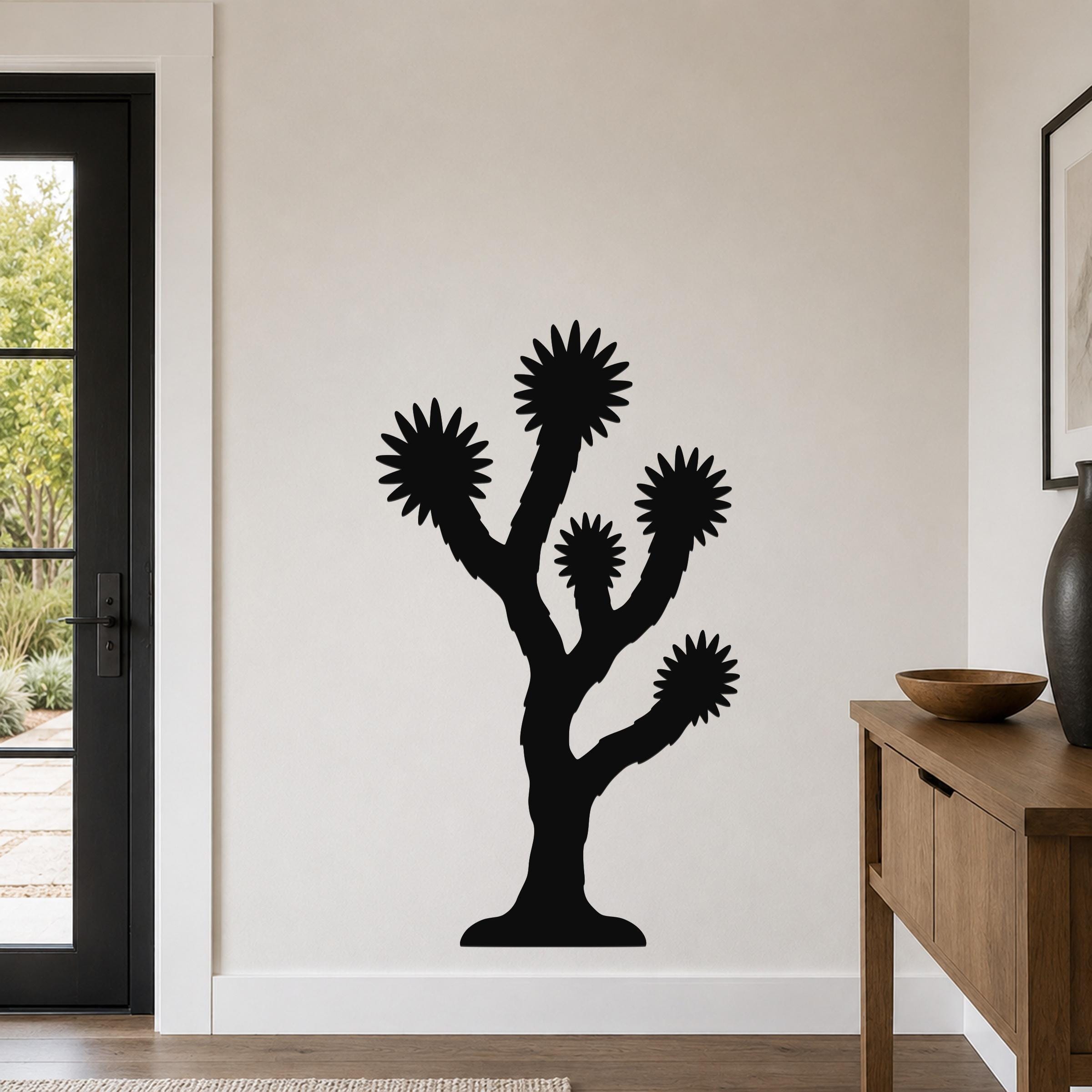 Black metal Joshua tree wall art with starburst-shaped branches, mounted on a white wall in a modern living room.