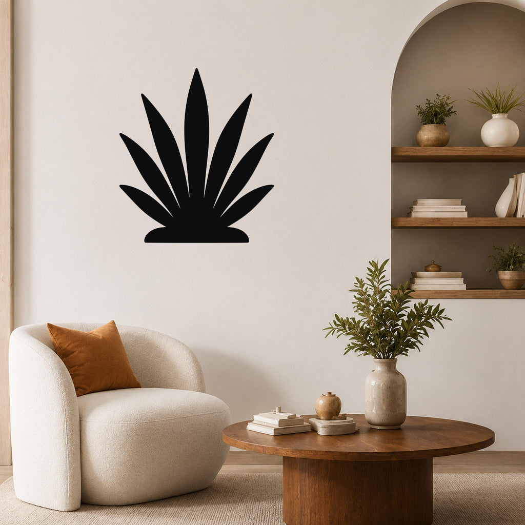 Black metal agave wall art silhouette mounted on a living room wall above a white armchair.