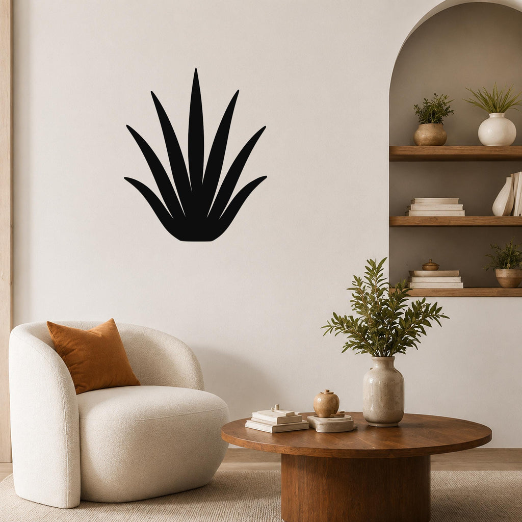 Black metal agave wall art with pointed leaf cutouts, mounted on a living room wall above a round wooden coffee table.