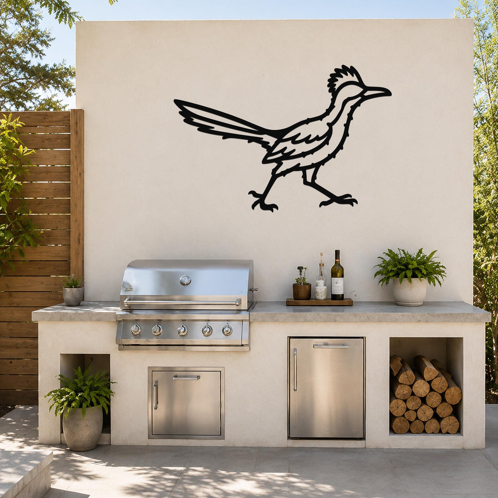 Black metal roadrunner wall art with cutout details, mounted on an outdoor patio wall above a stainless steel grill and countertop.