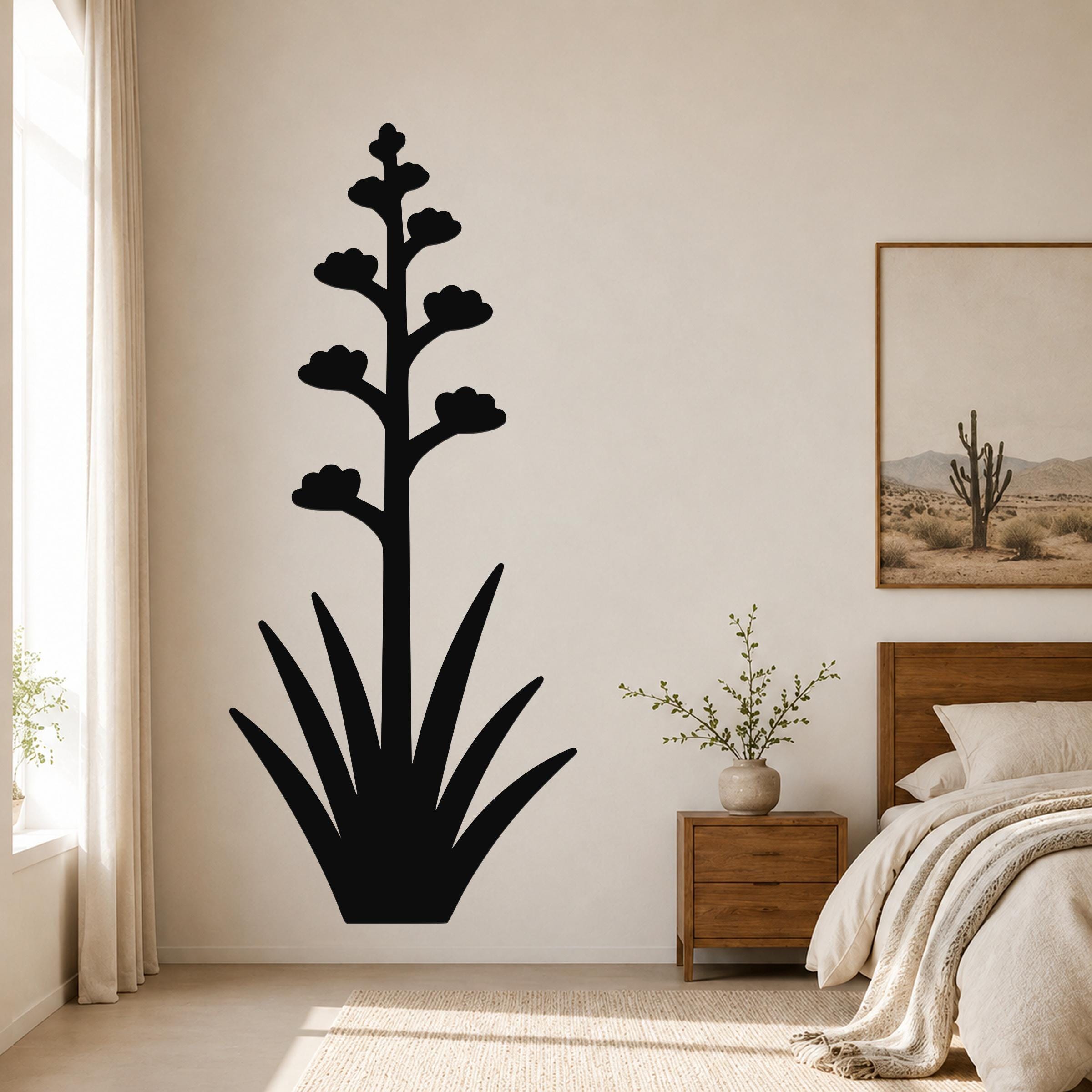 Black metal wall art in the silhouette of a blooming agave plant with a tall flower stalk and spiky leaves, mounted on a bedroom wall above a nightstand.