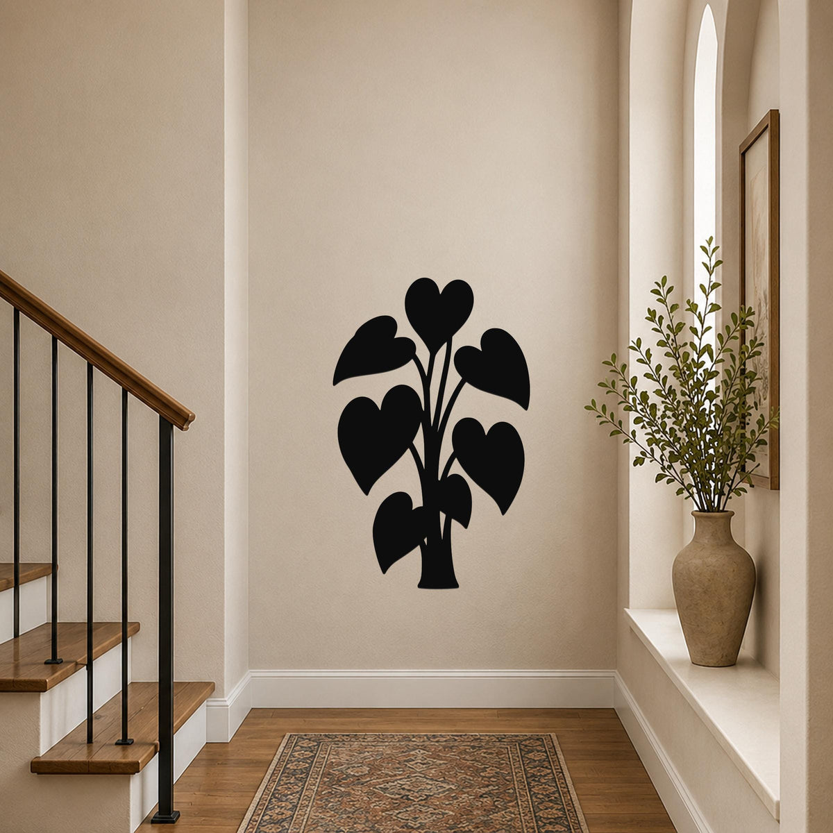 Black metal wall art in a heart-shaped philodendron silhouette, mounted on a hallway wall above a patterned rug near a staircase.