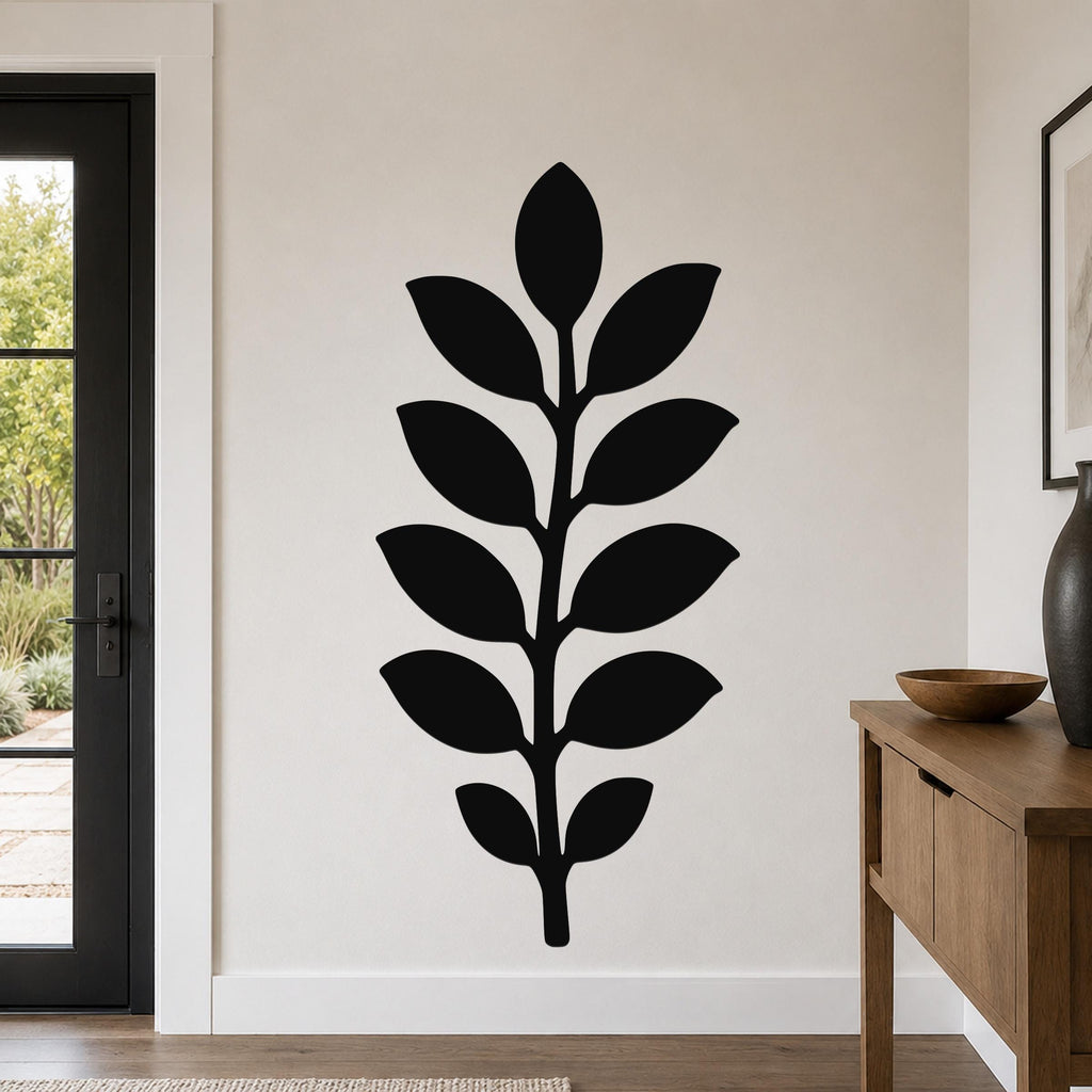 Black metal wall art in a leafy branch silhouette, mounted on a light-colored wall in a modern entryway.