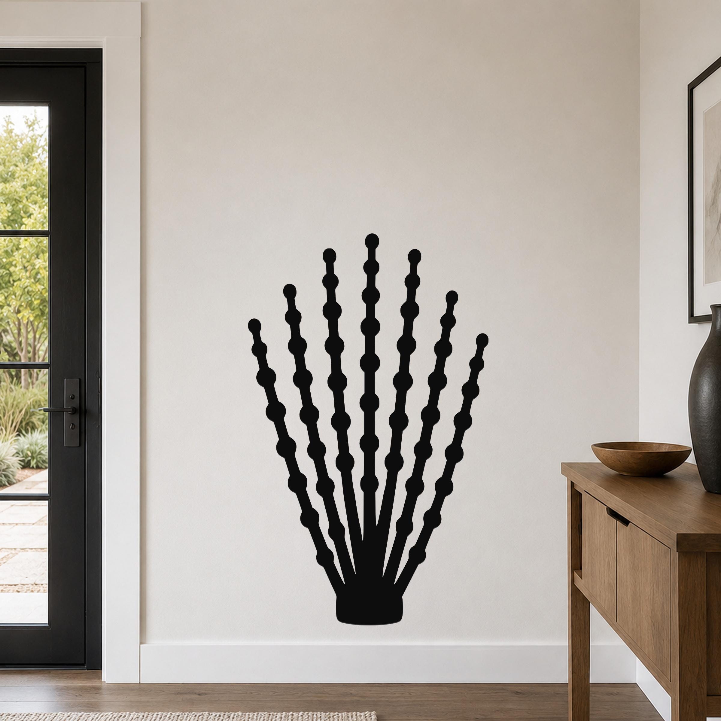Black metal ocotillo wall art with beaded branch cutouts, mounted on a white wall above a wooden console in a modern entryway.