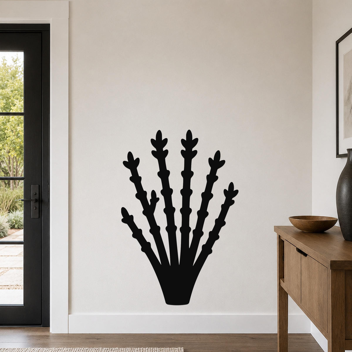 Black metal ocotillo wall art with branching cutouts, mounted on a white wall in a living room near a door and console table.