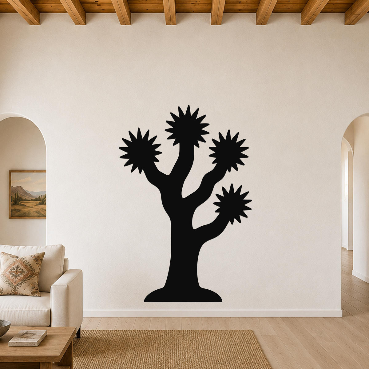 Black metal Joshua tree wall art with starburst-shaped branches, mounted on a living room wall above a sofa.