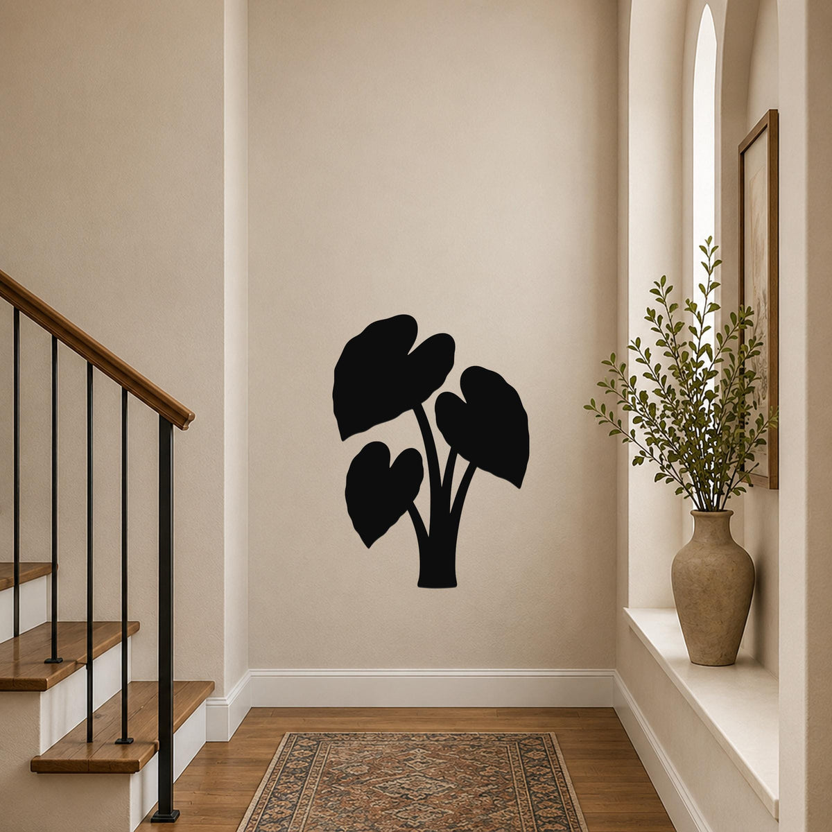 Black metal wall art in the silhouette of an elephant ear plant, mounted on a beige hallway wall above a patterned rug near a staircase.