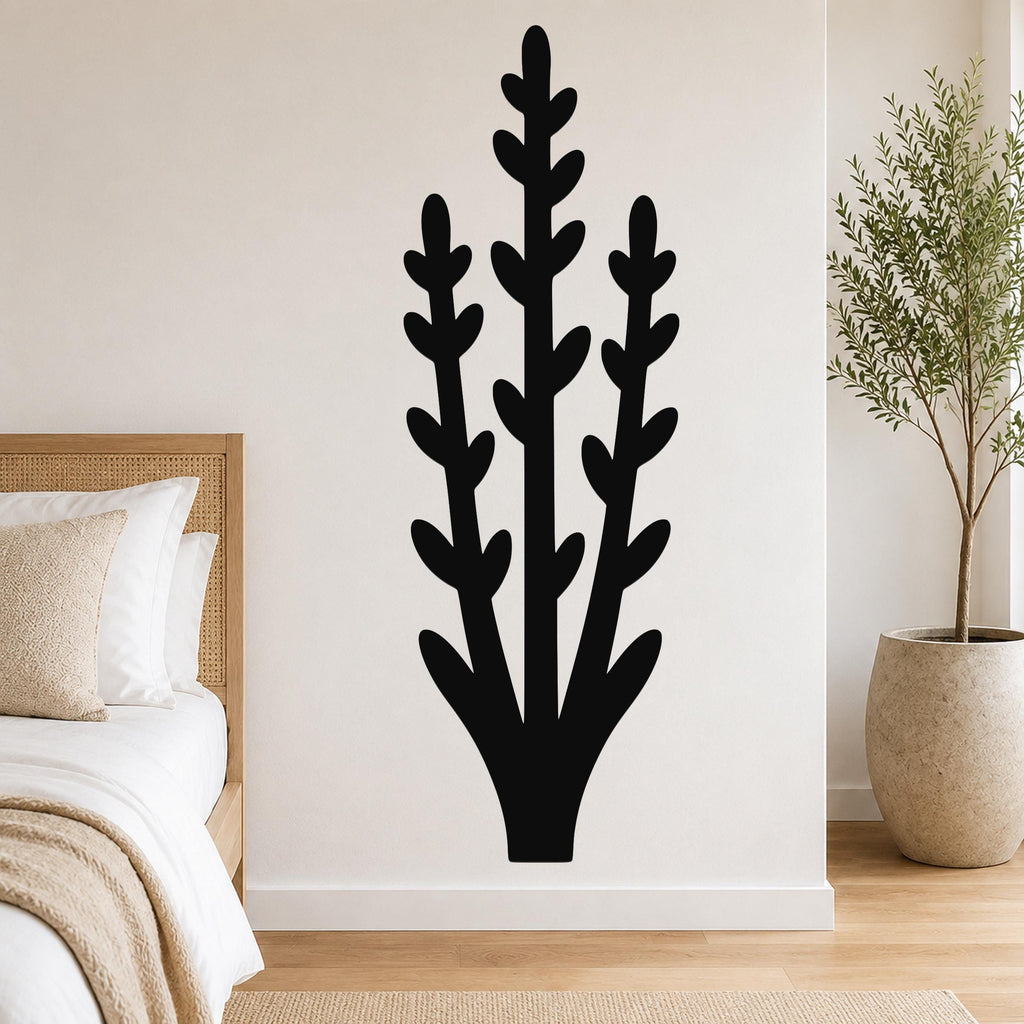 Black metal wall art in a silhouette of an abstract desert plant with three tall stems and leaf cutouts, mounted on a white wall above a bed in a bedroom.