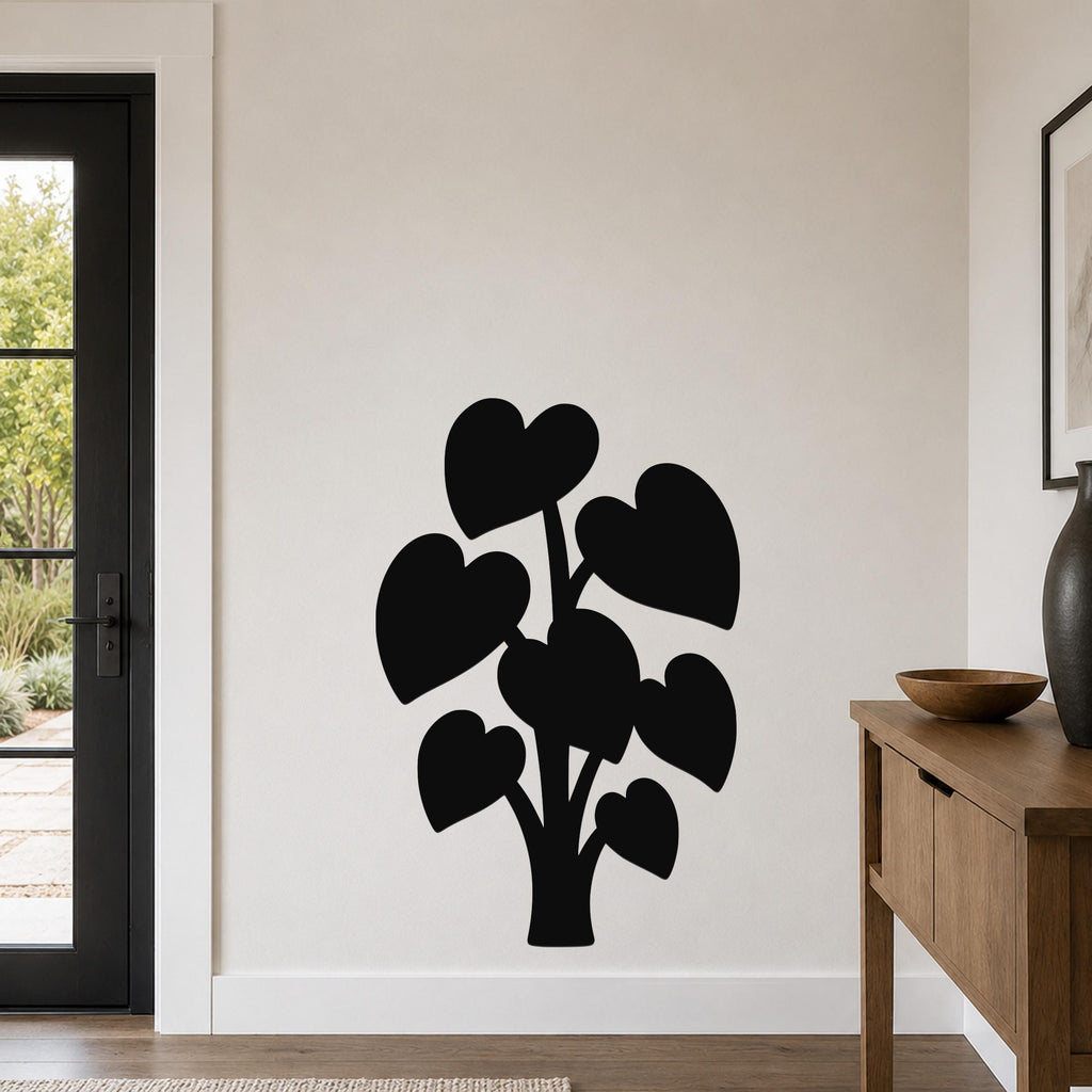 Black metal wall art in the silhouette of an elephant ear plant with heart-shaped leaves, mounted on a light-colored wall in a modern entryway.