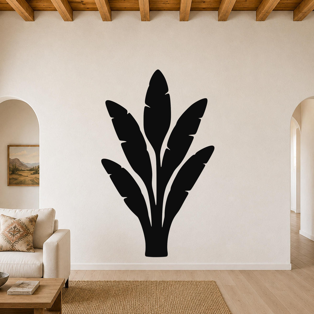 Black metal banana plant wall art with leaf cutouts, mounted on a living room wall above a sofa.