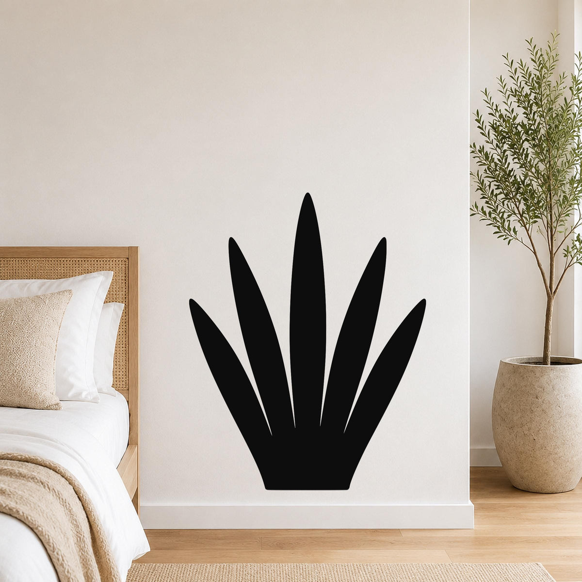 Black metal wall art in a silhouette of a century plant with spiky leaves, mounted on a white bedroom wall above a bed.