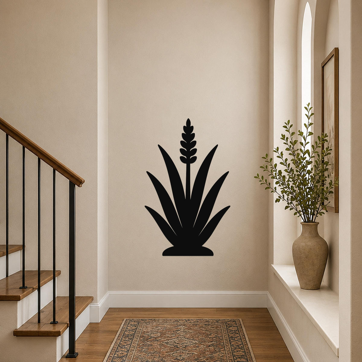 Black metal agave wall art with a central flower spike cutout, mounted on a hallway wall above a patterned rug near a staircase.