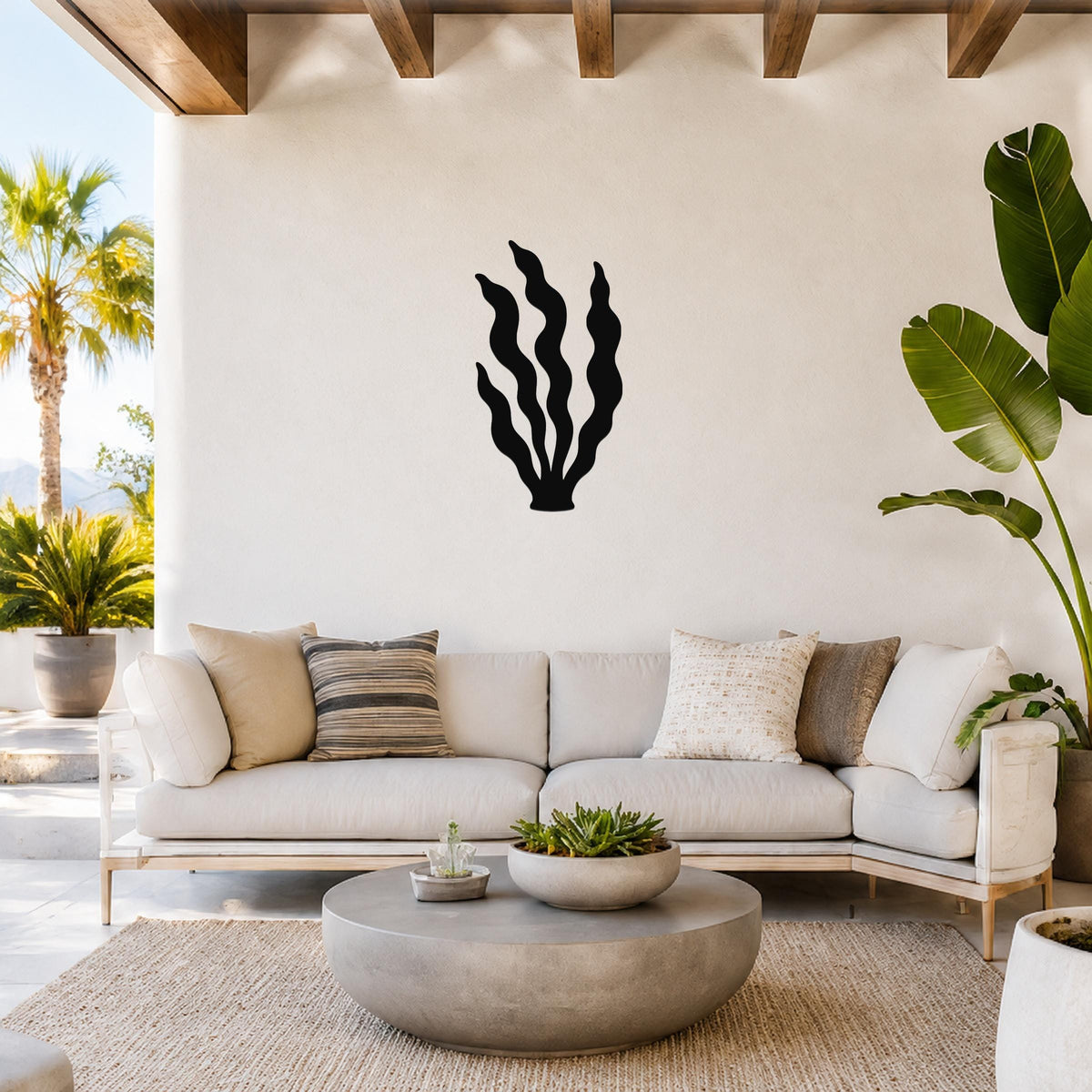 Black metal kelp wall art with wavy frond cutouts, mounted on a white wall above a light-colored sofa in a bright living room.
