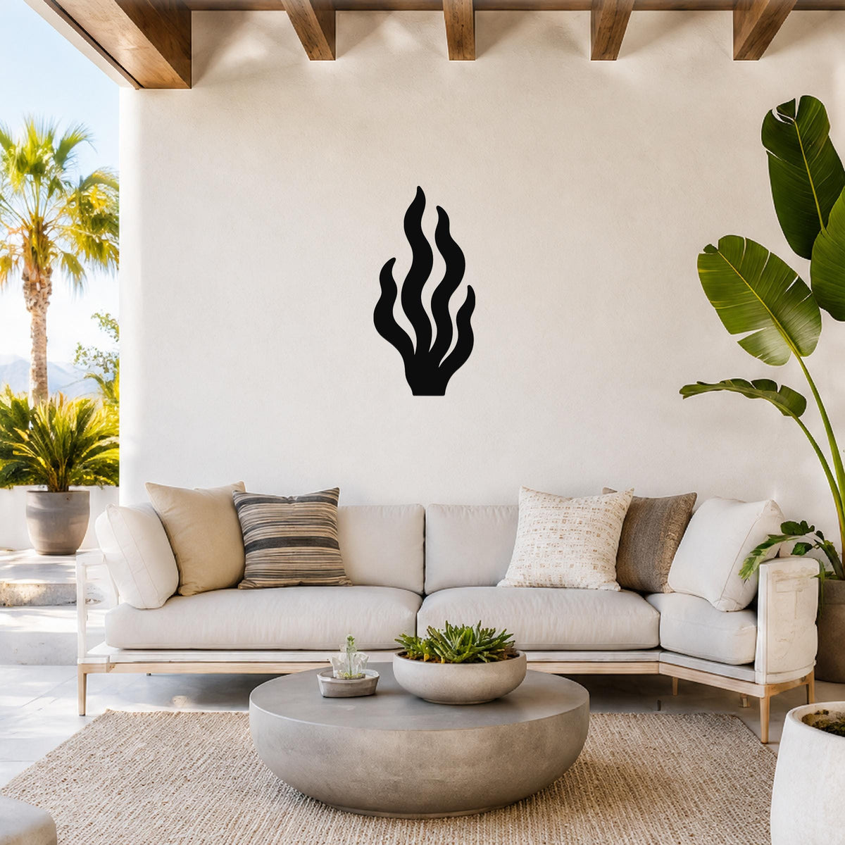 Black metal kelp wall art with flowing frond cutouts, mounted on a white wall above a light-colored sofa in a bright living room.