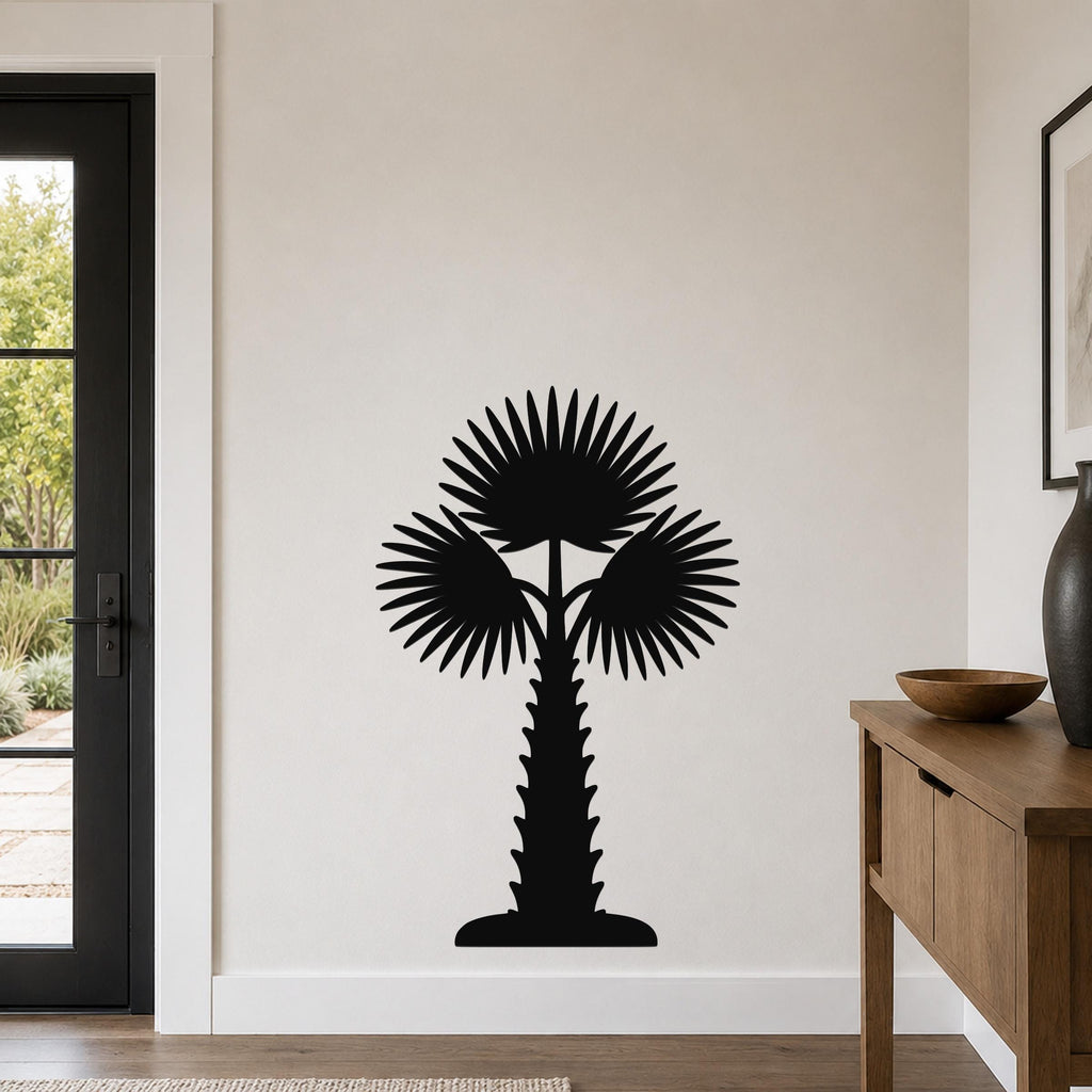 Black metal palm tree wall art with fan-shaped fronds and a textured trunk, mounted on a light-colored wall in a modern entryway.