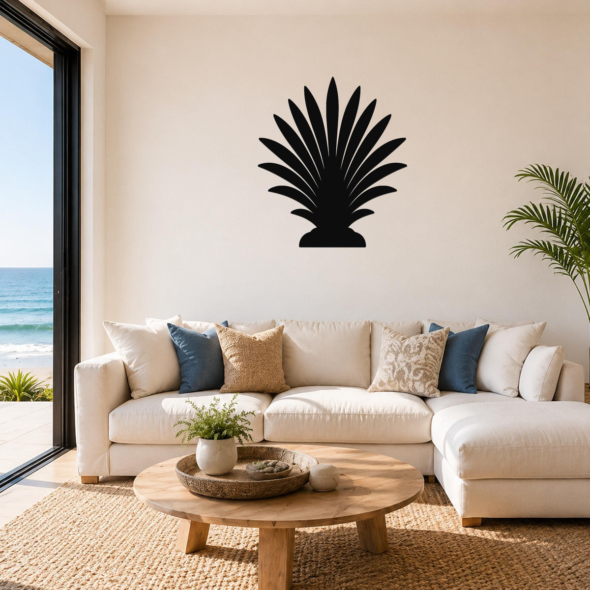 Black metal palm tree wall art with fan-shaped fronds, mounted above a white sofa in a living room with ocean views.