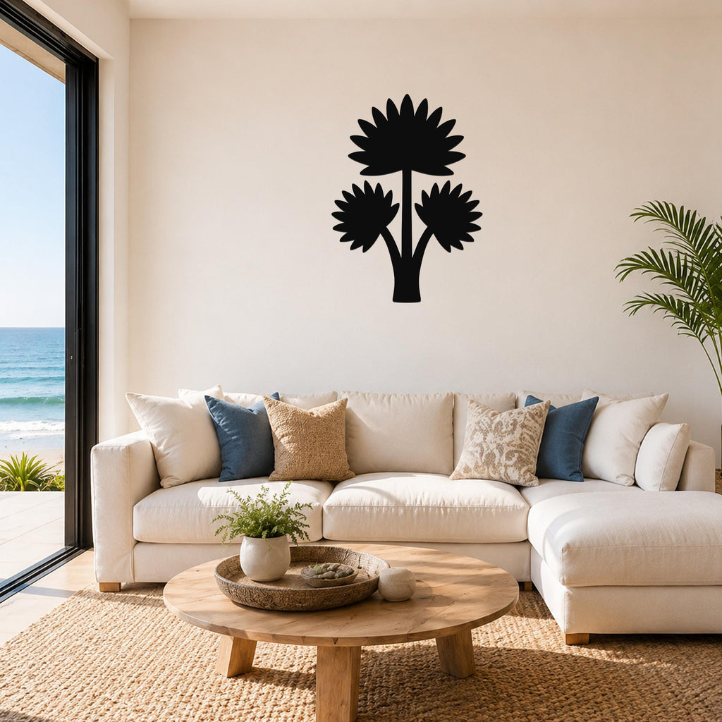 Black metal wall art in a fan palm tree silhouette with three leafy fronds, mounted above a white sofa in a living room with ocean views.