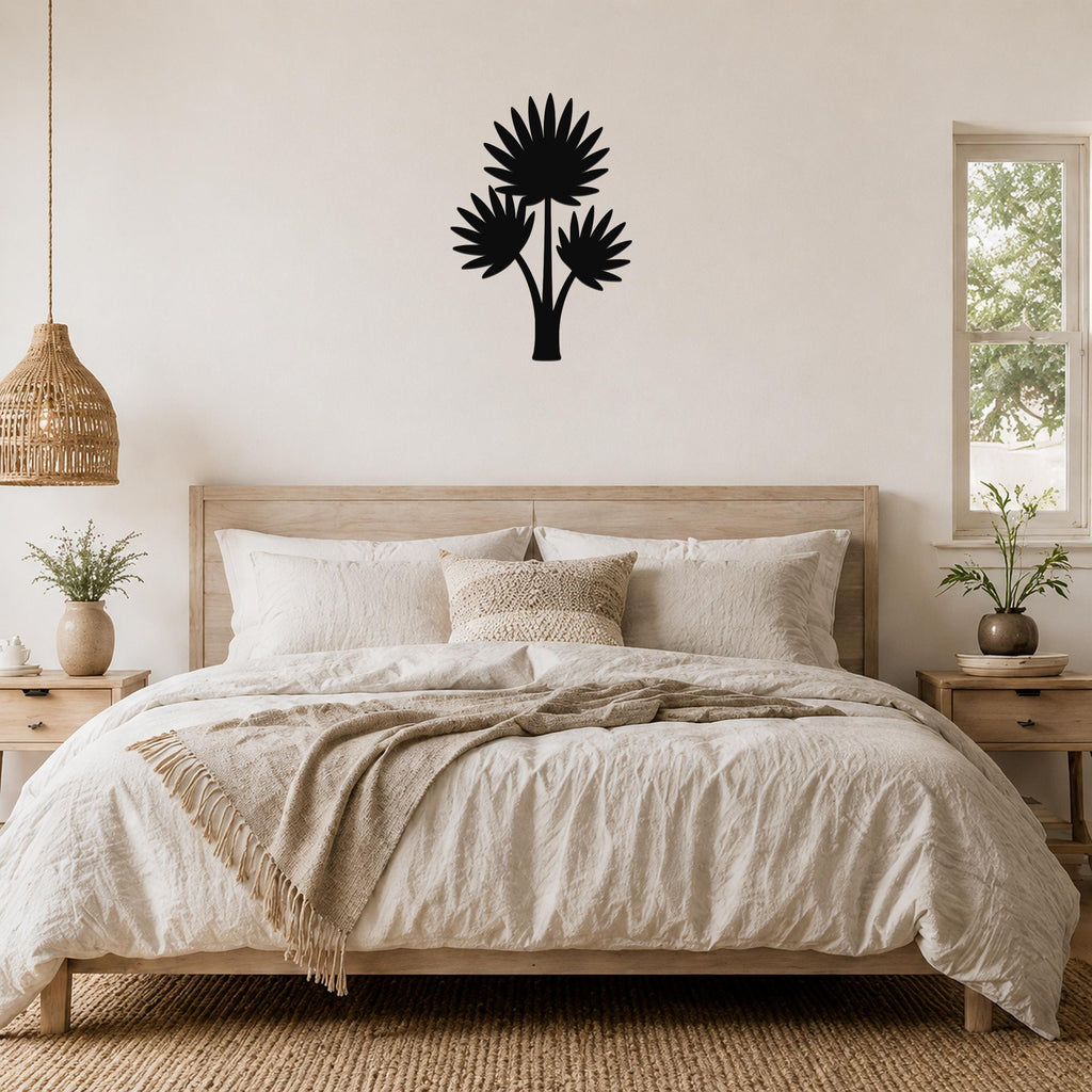 Black metal wall art silhouette of a fan palm tree with three fronds, mounted on a wall above a bed in a neutral bedroom.