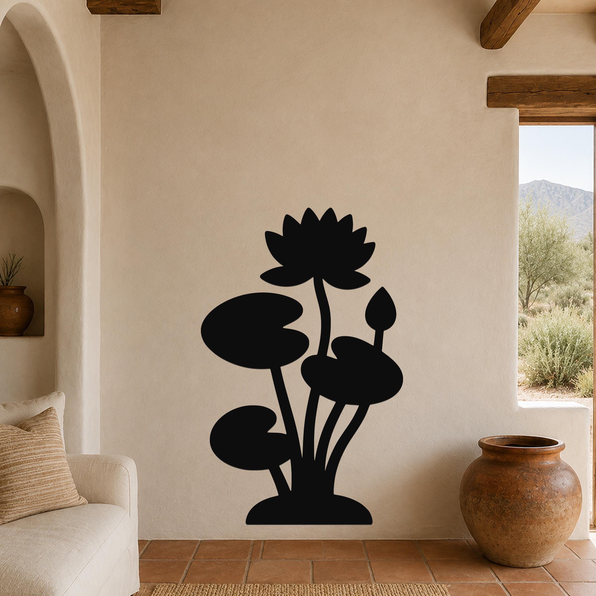 Black metal lotus water lily wall art with silhouette cutouts of flowers and leaves, mounted on a beige living room wall above a sofa.
