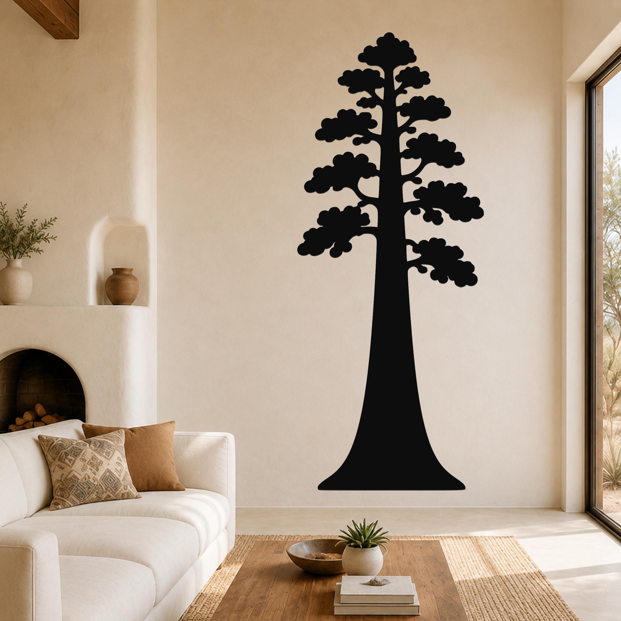 Black metal sequoia tree wall art with layered branch cutouts, mounted on a living room wall above a white sofa.
