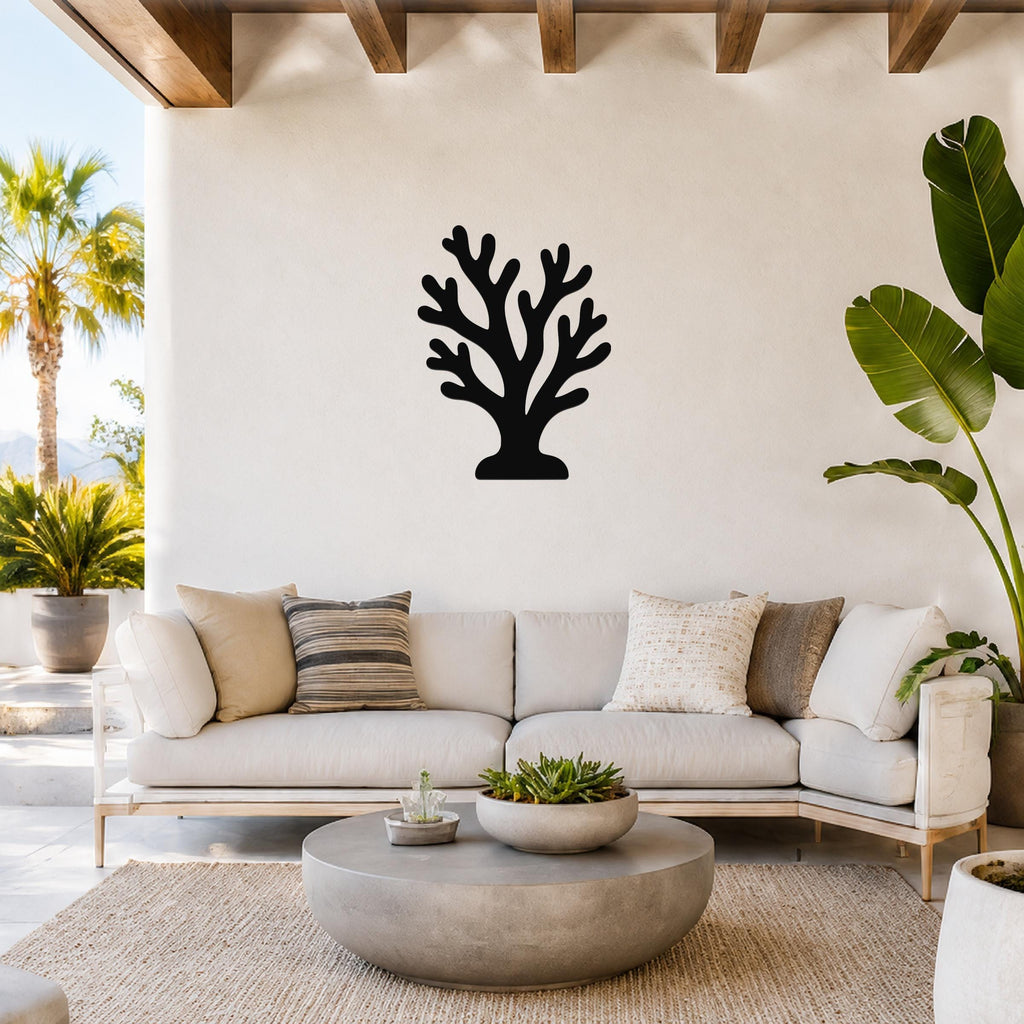 Black metal coral wall art with branching cutouts, mounted on a light-colored wall above a wooden console in a minimalist living room.