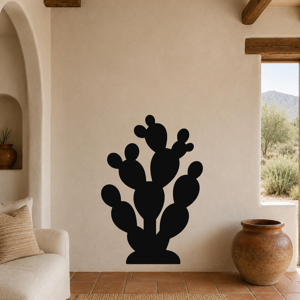 Black metal prickly pear cactus wall art with multiple rounded pads and cutout details, mounted on a beige living room wall above a sofa.