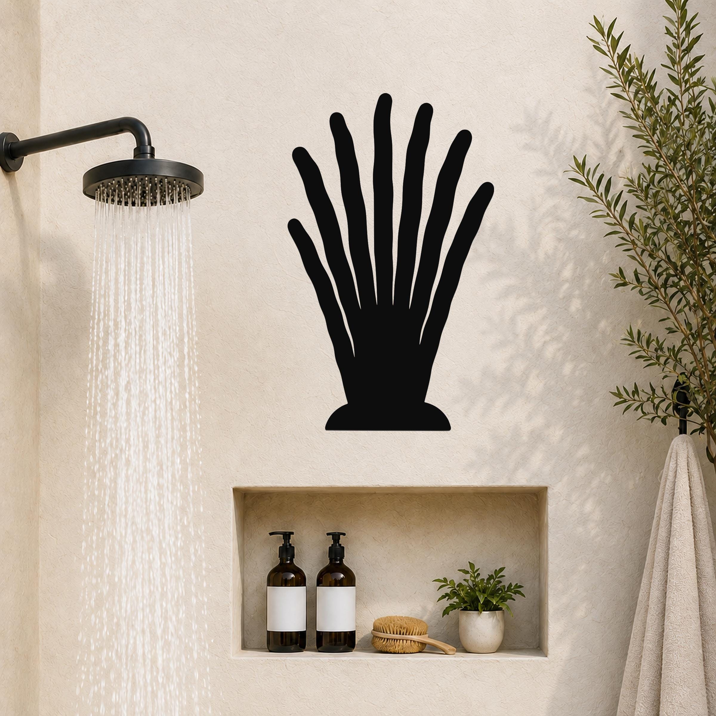 Black metal wall art in a silhouette of a hand with spread fingers, mounted on a bathroom wall above a built-in shelf.
