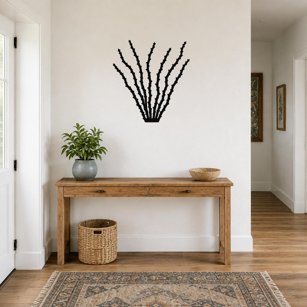 Black metal ocotillo wall art with spiky branch cutouts, mounted above a wooden console table in a bright entryway.