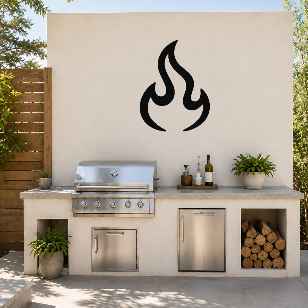 Black metal flame silhouette wall art mounted on a light-colored outdoor wall above a stainless steel grill and countertop.