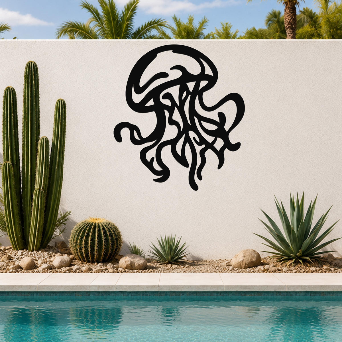 Black metal jellyfish wall art with flowing tentacle cutouts, mounted on a white outdoor wall beside a pool and desert plants.