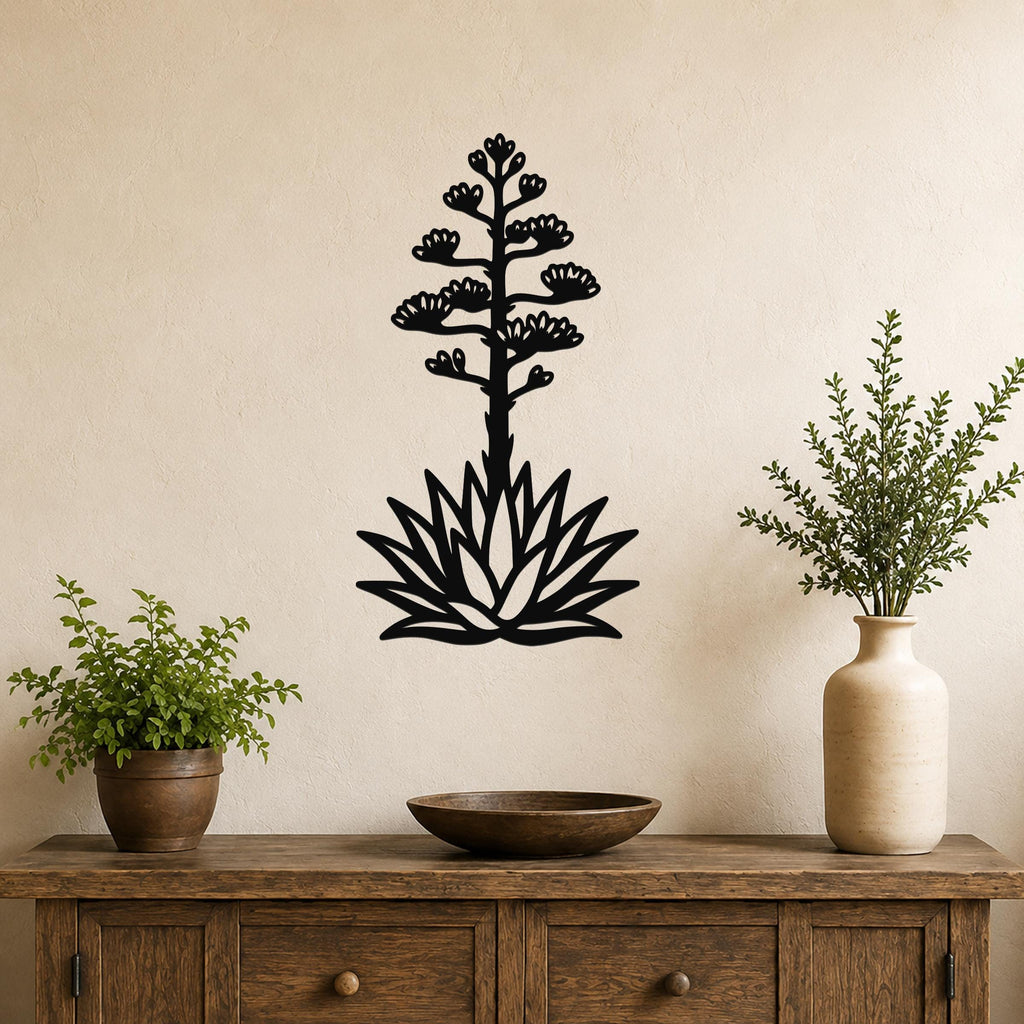 Black metal agave wall sculpture with blooming flower cutouts, mounted on a beige wall above a wooden console table.
