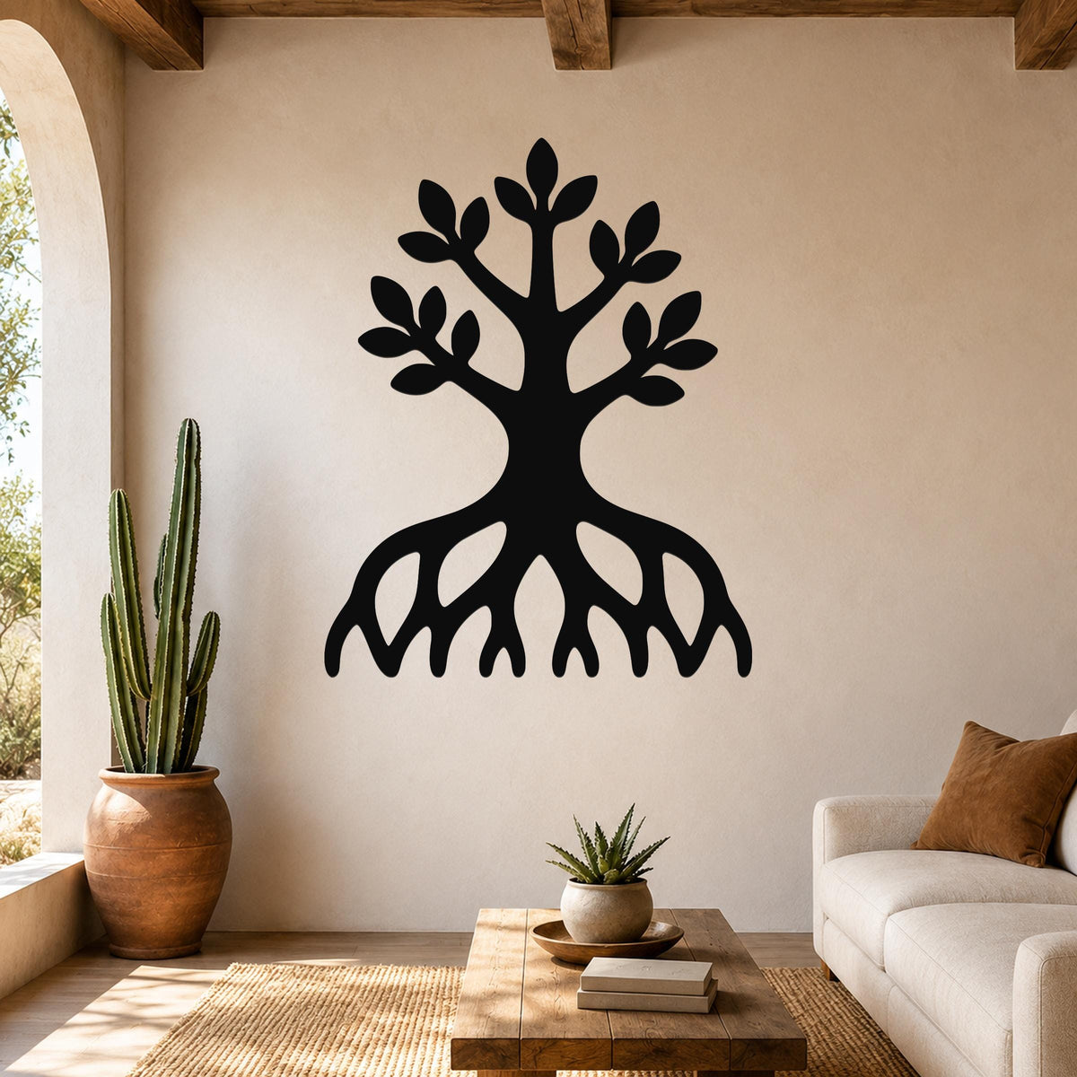 Black metal wall art in a tree silhouette with visible roots and leafy branches, mounted on a beige living room wall above a wooden coffee table.